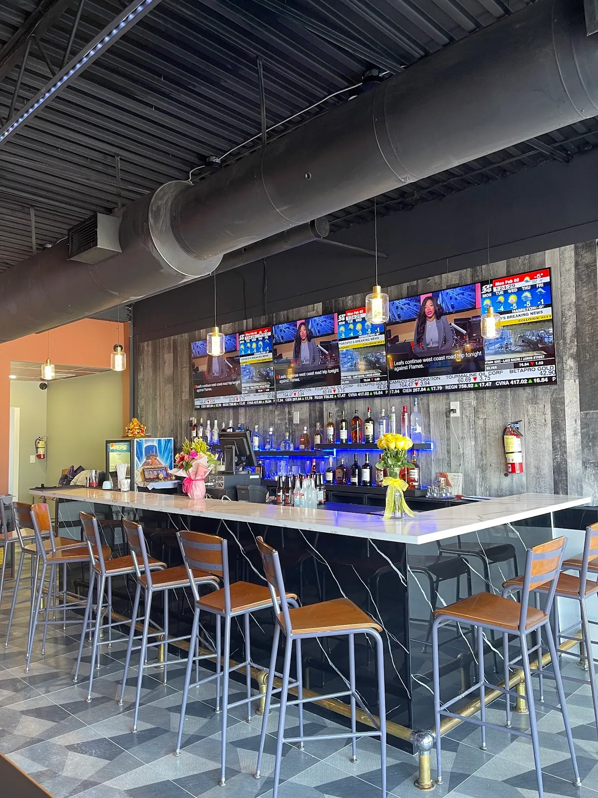 The long marble bar at Dailyn, stools pulled in and pendant lights on