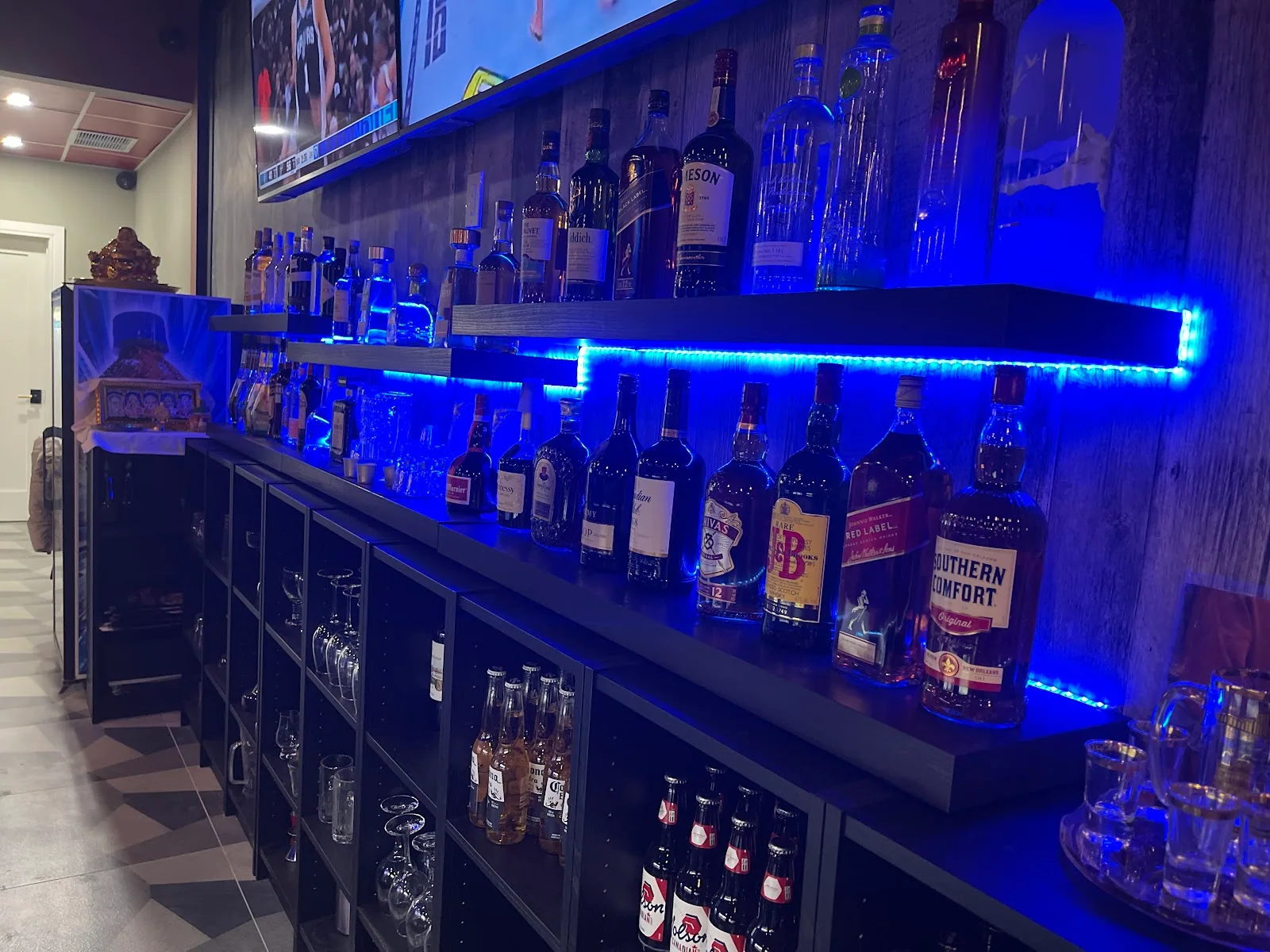 Backlit liquor shelves glowing blue behind the Dailyn bar