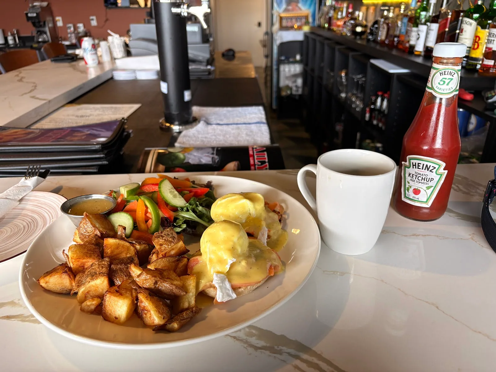 Eggs benedict with home fries and a coffee on the bar counter