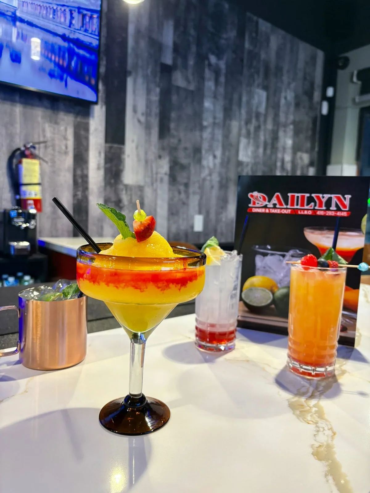 Three cocktails including a frozen strawberry margarita on the Dailyn bar