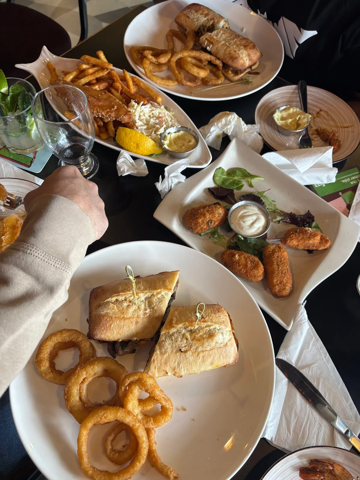 A table of fish and chips, steak sandwiches, onion rings and mozzarella sticks